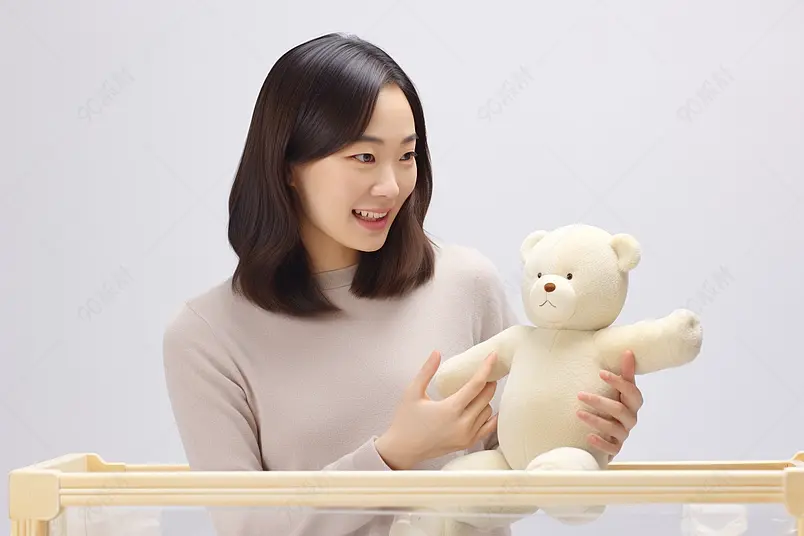 月嫂年轻妈妈用毛绒玩具逗宝宝开心高清摄影图